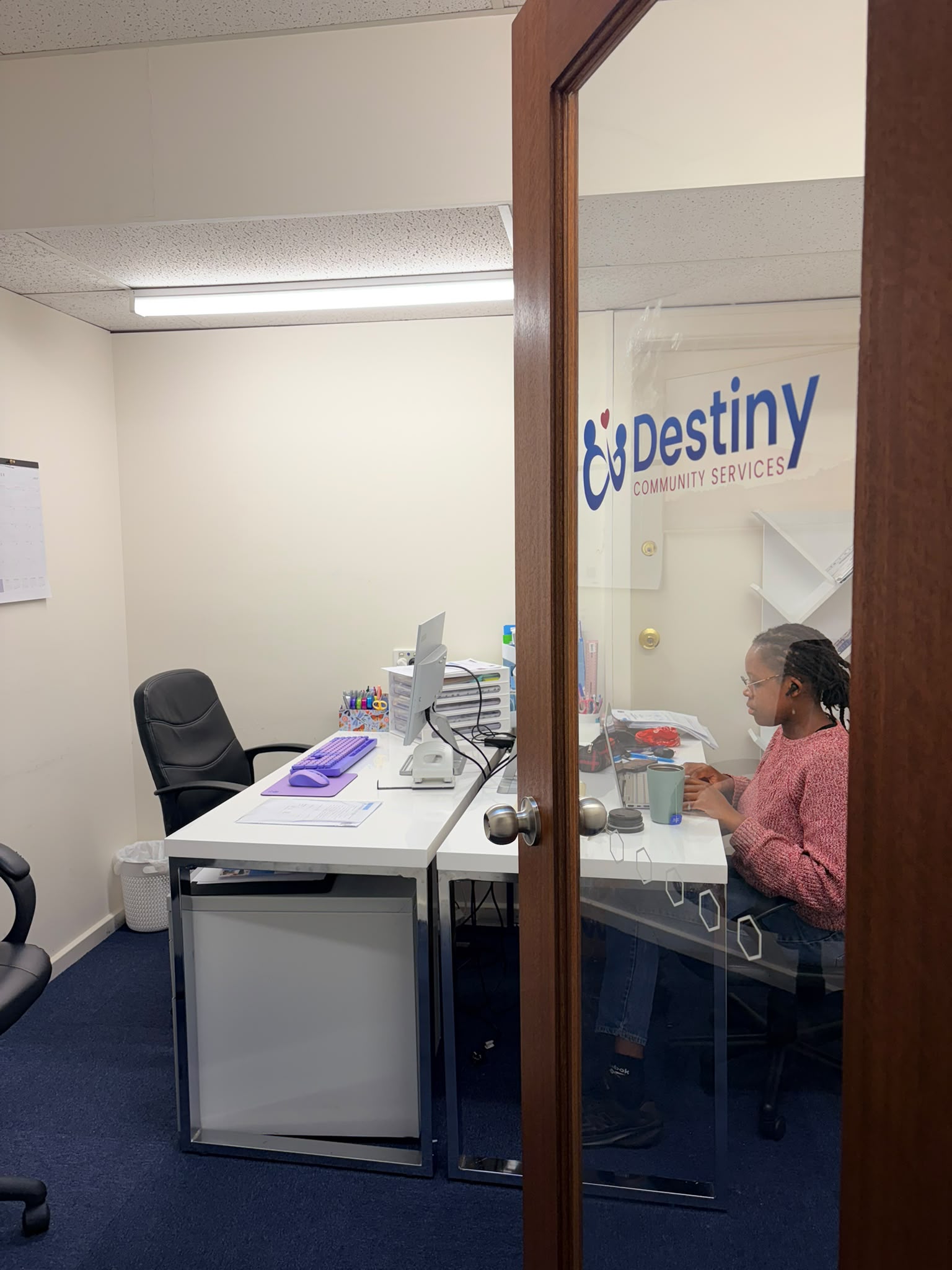 Destiny Community Services branded glass door with team member visible